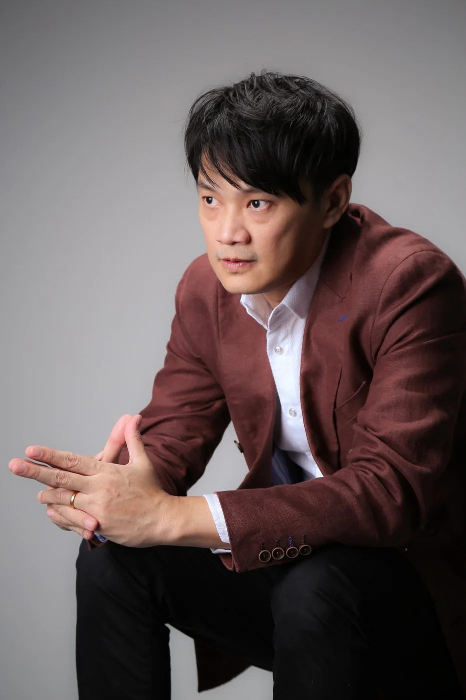 Lucian Yong seated, hands together, thinking