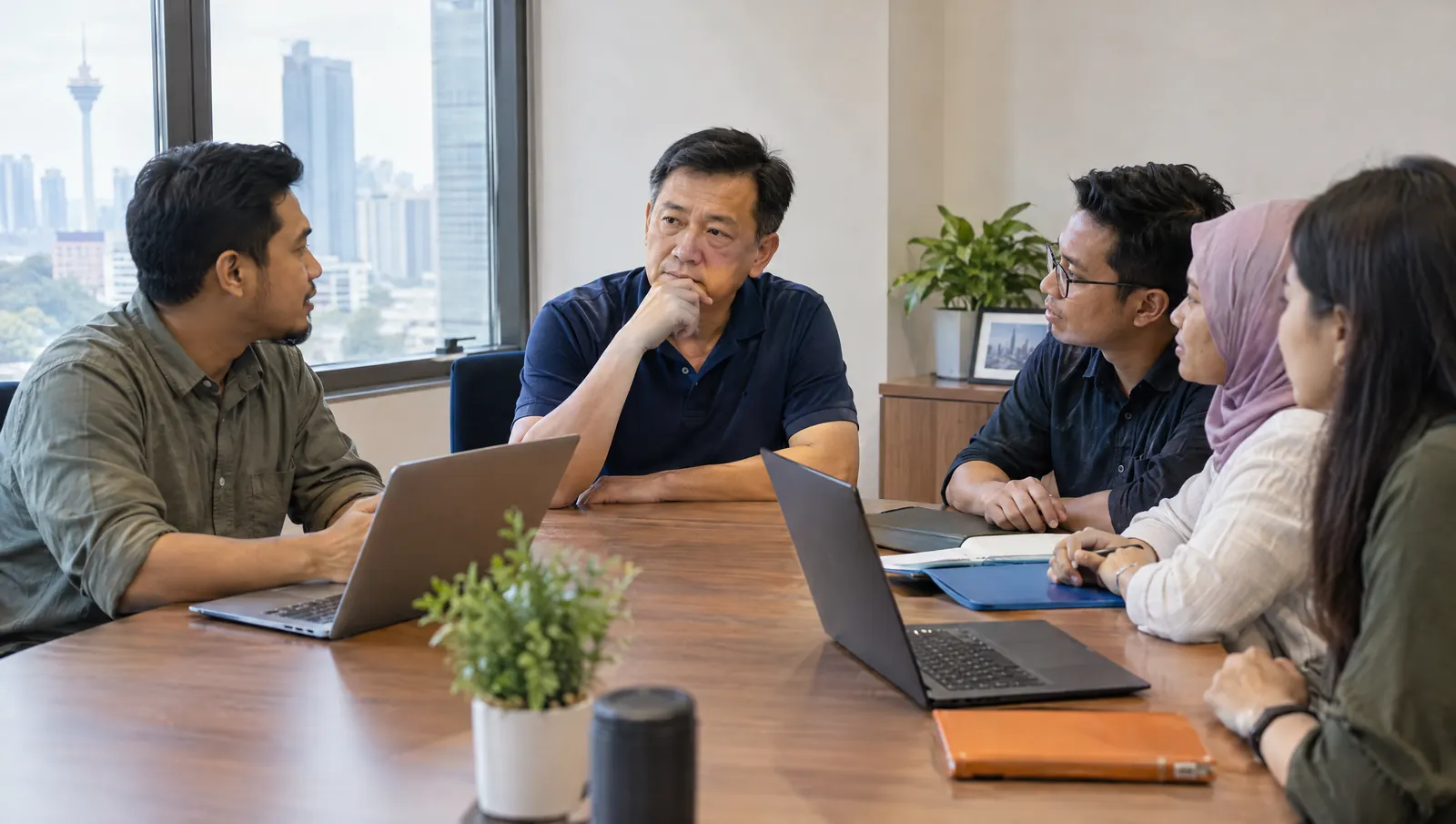 Pemilik perniagaan Malaysia dalam mesyuarat, membandingkan freelance web designer dan pasukan agensi web design